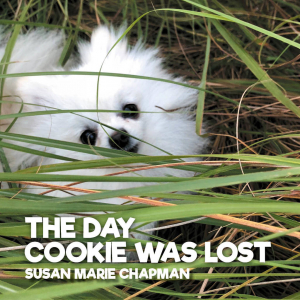 It is a photo of Cookie surrounded by blades of grass (small white Pomeranian